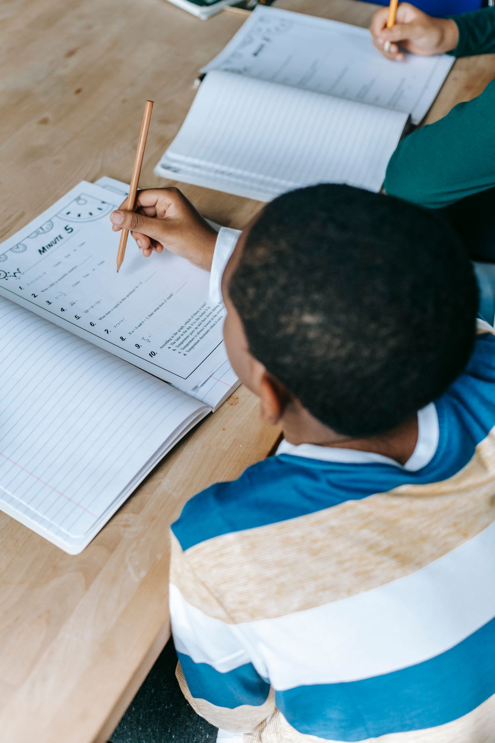 A pupil completing written work at a classroom desk